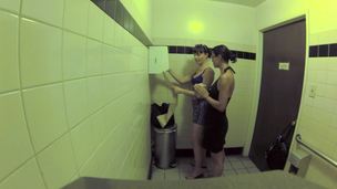 Two bitches are in the public bathroom, licking one another